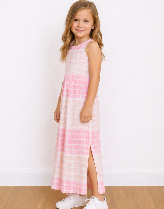 A young girl with blonde hair stands in a studio wearing a sleeveless pink and white tie-dye Maxi Tank Dress with a side slit, paired with white sneakers.