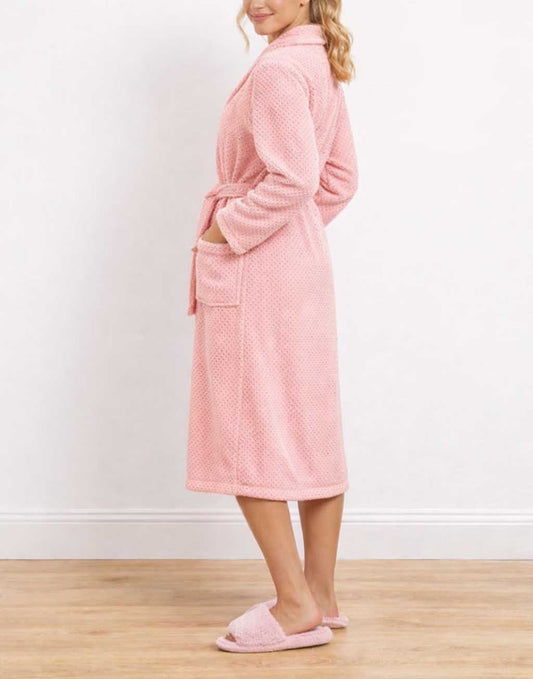 Side view of woman wearing a pink Shawl Collar Bathrobe and matching slippers on a wooden floor.