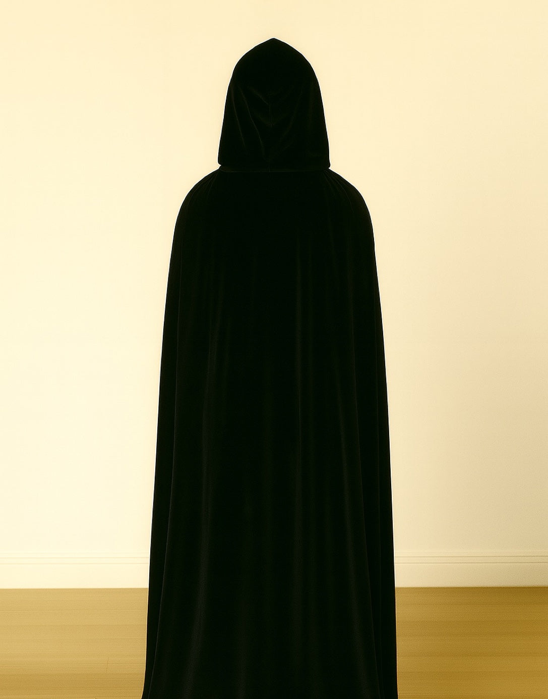 Back view of person wearing a black hooded cloak against a plain background
