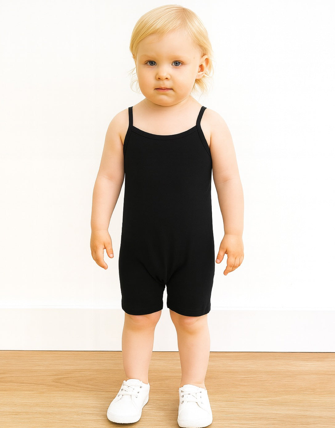 Child wearing a black Cami Unitard Romper on a white background