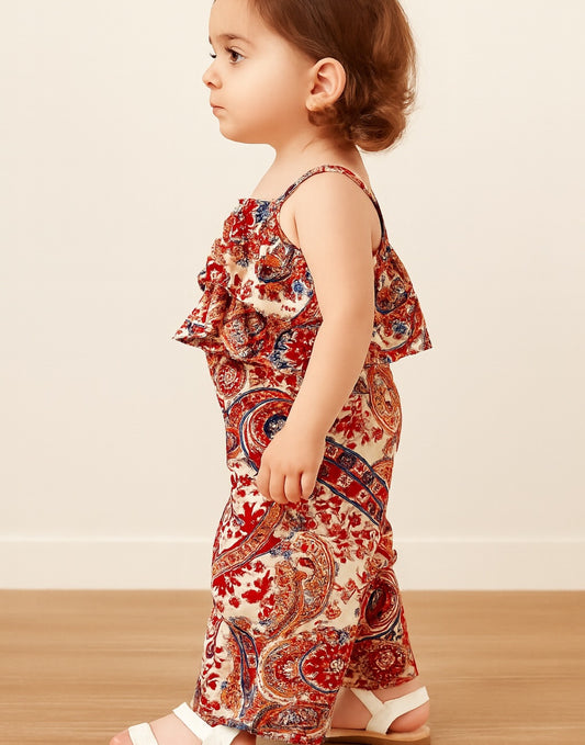 Side view of child wearing a red and beige patterned Ruffle Hem Cami Top and Wide Leg Pants Set on a wooden floor with a beige wall background