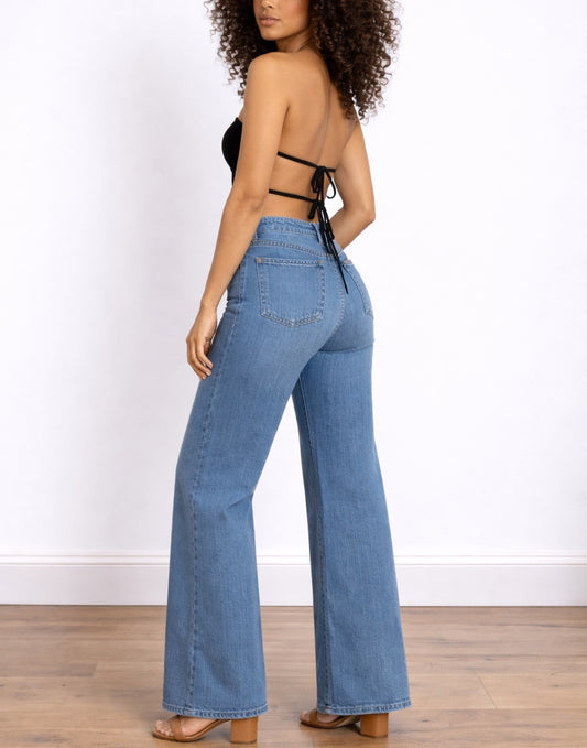 Side view of woman wearing a black Backless Tube Top and blue jeans on a white background.