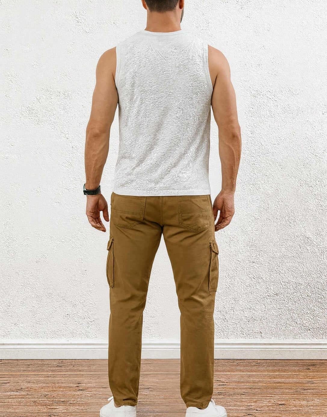 Back view of man wearing a Round Neck Tank Top and brown pants against a white textured wall.