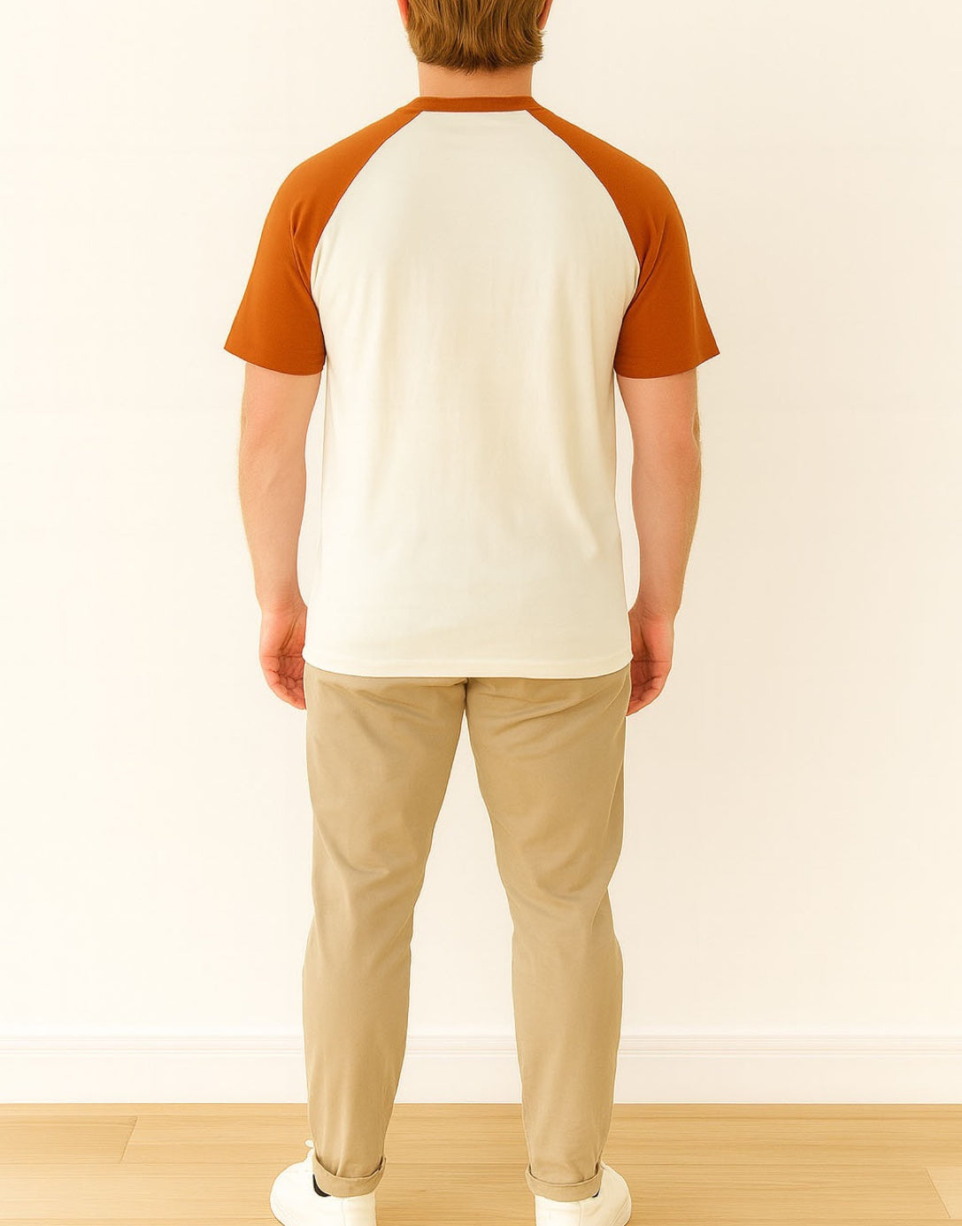 Back view of person wearing a white and brown Crew Neck Raglan Short Sleeve T-Shirt with beige pants on a light wooden floor.