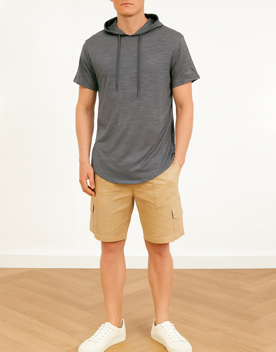 Person wearing a gray hoodie tee and beige shorts on a white background