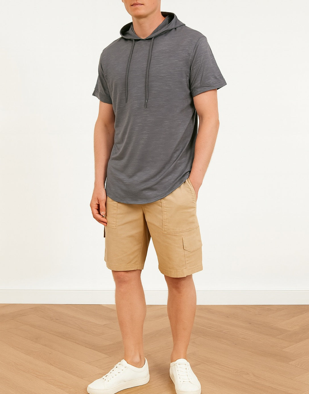 Side view of person wearing a gray hoodie t-shirt and beige shorts on a white background.