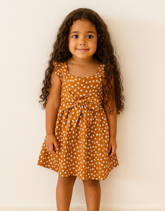 Young girl wearing a polka dot Bow Front Cami Dress against a plain background