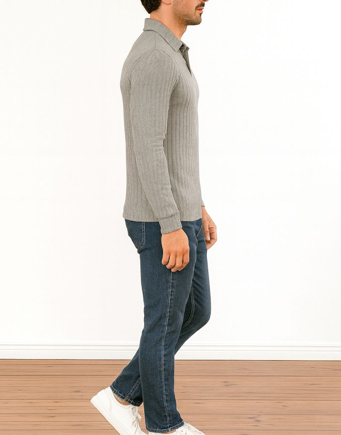 Side view of man wearing a gray Long Sleeve Polo Shirt and blue jeans standing on a wooden floor with a white wall background