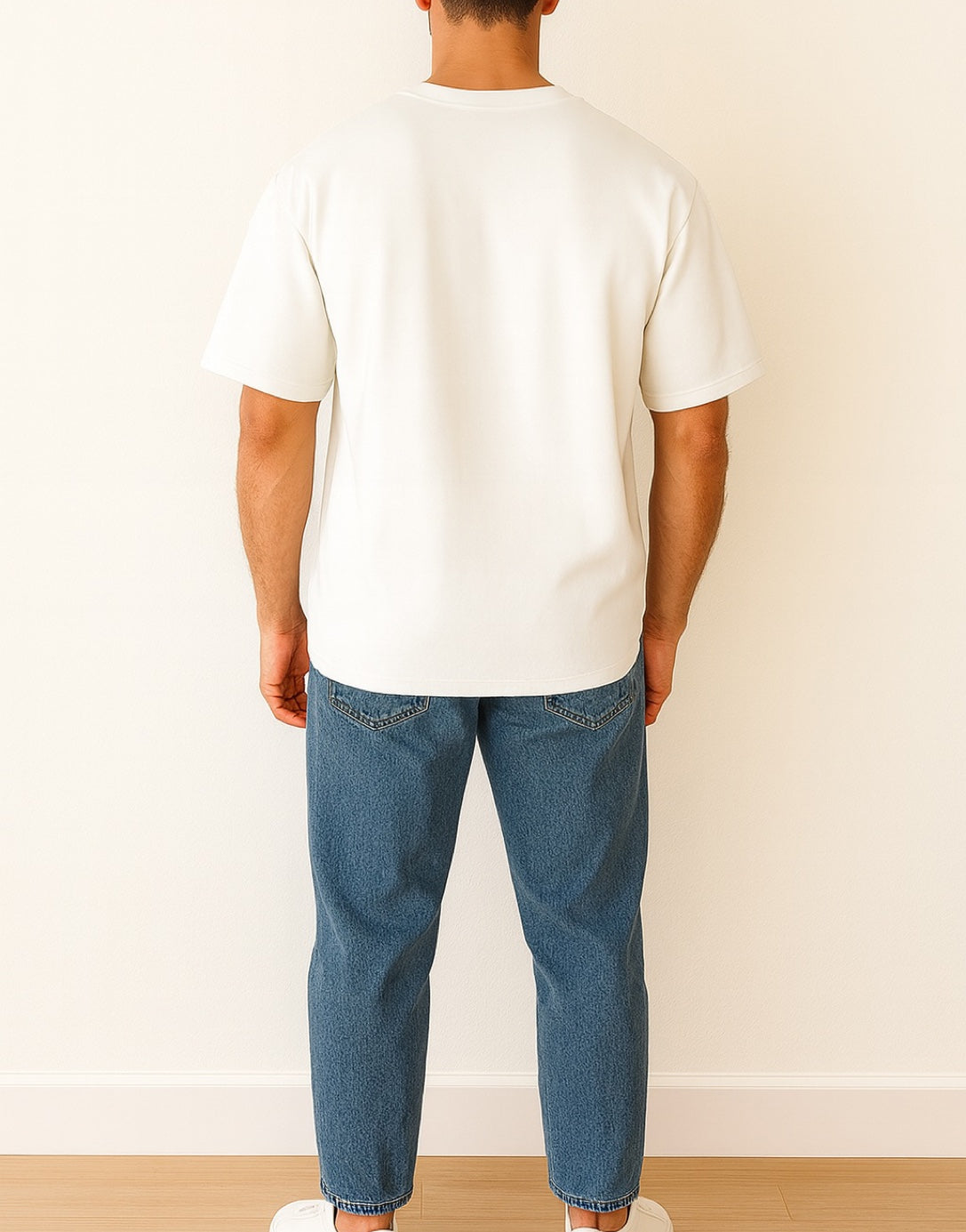 Back view of person wearing a plain white Oversized T-Shirt against a blue background