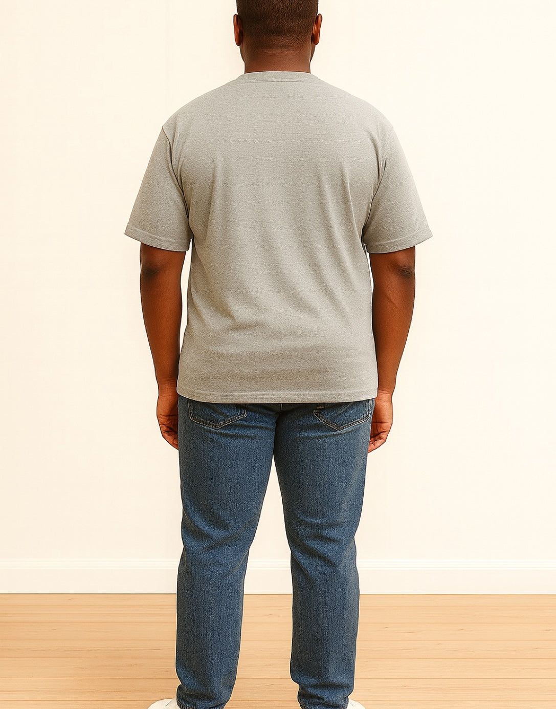 Back view of man wearing a beige Oversized Shirt and blue jeans standing on a wooden floor with a white wall background