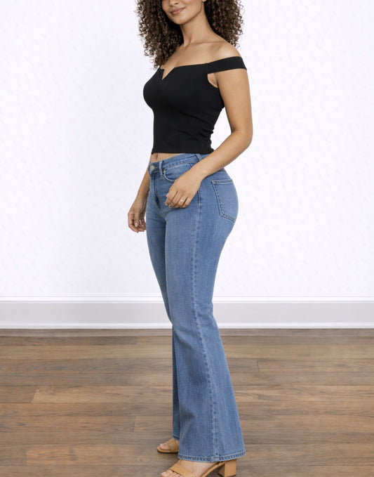 Side view of woman wearing a black Off Shoulder Tank Top and blue flared jeans on a white background.