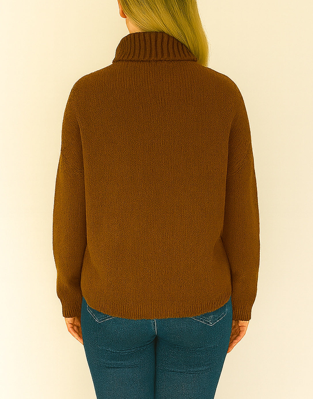 Back view of person wearing brown Oversized Turtleneck Sweater and blue jeans standing in front of a plain background.