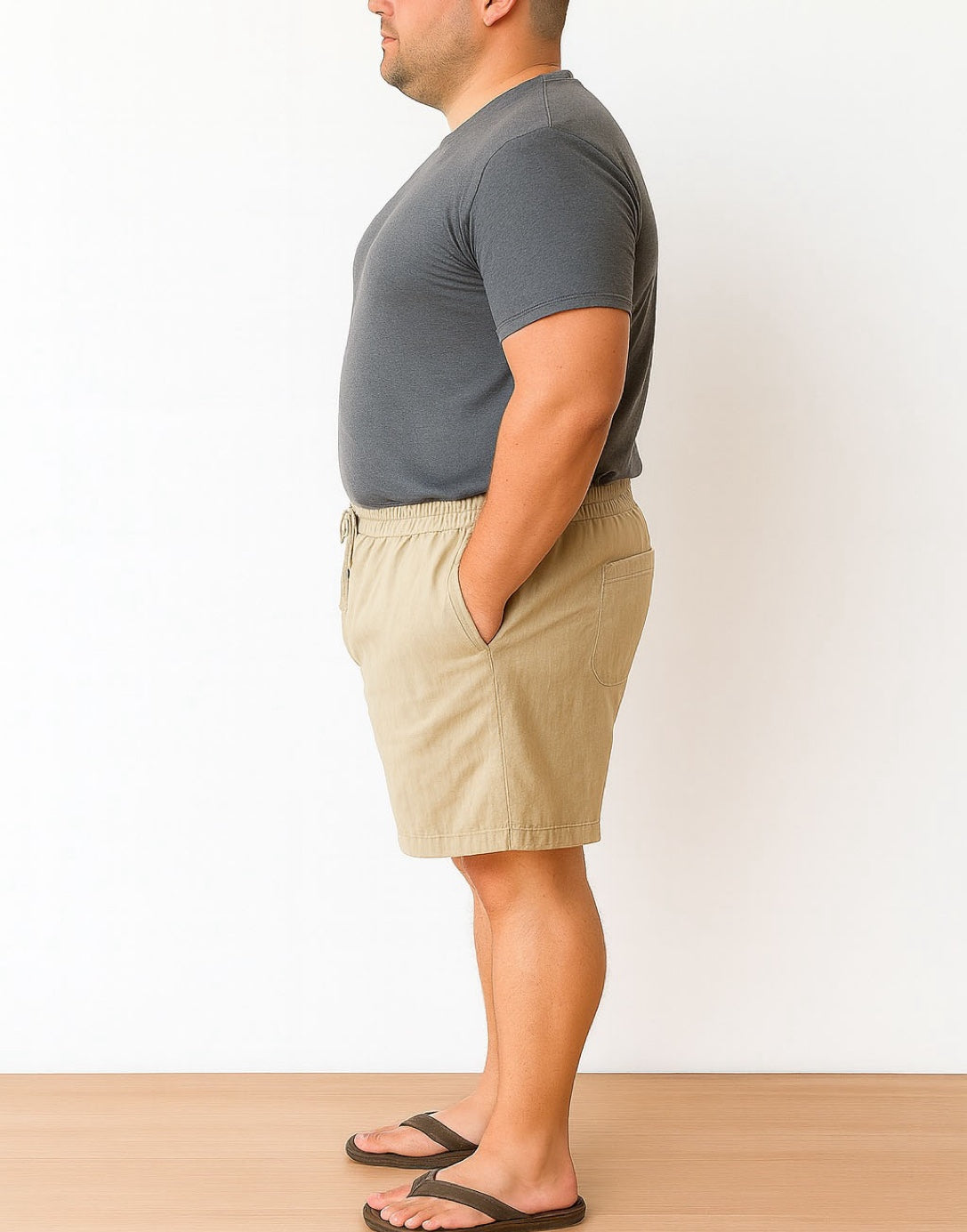 Side view of man wearing a gray t-shirt and beige Plus Size Drawstring Button Front Shorts against a white background.