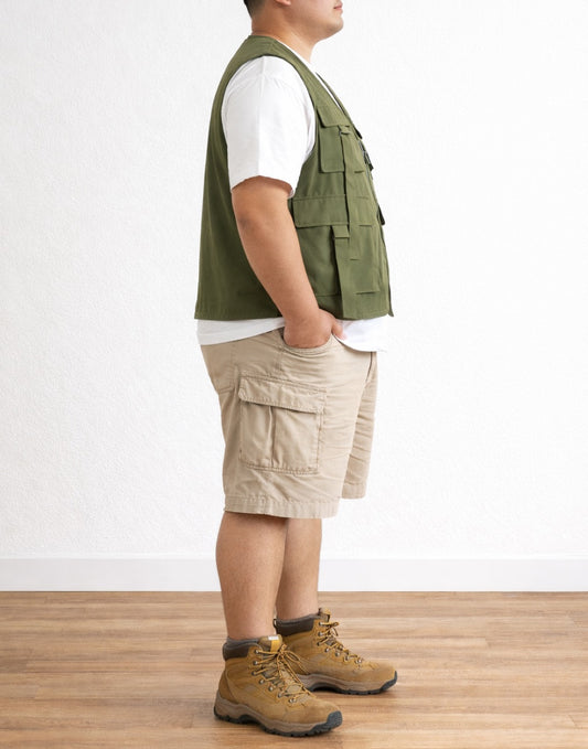 Side view of person wearing a green Plus Size Men Cargo Pocket Vest, white shirt, beige shorts, and brown boots on a plain background.