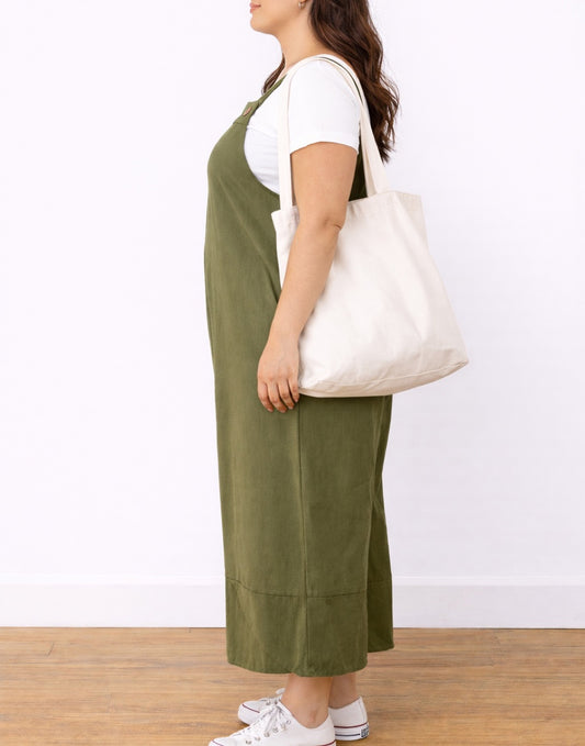 Side view of woman wearing green Plus Size Shoulder Strap Pocket Overall Jumpsuit with a white background.