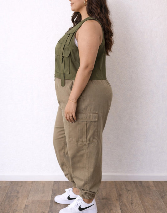 Side view of woman wearing a green Plus Size Women Cargo Pocket Vest and beige pants against a white background.