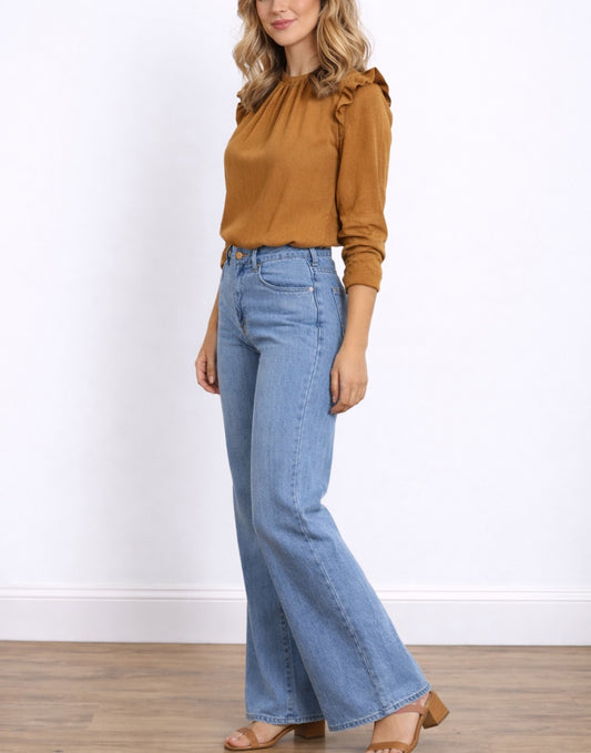 Side view of woman wearing a mustard yellow Ruffle Trim Button Back Blouse and blue jeans on a white background.