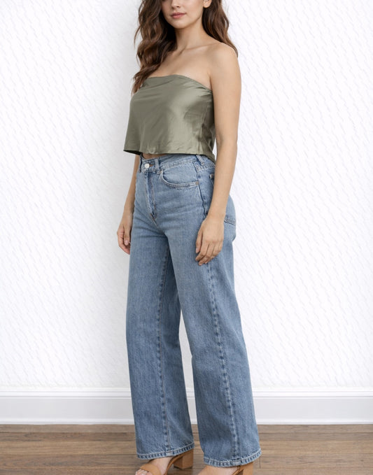 Side view of woman wearing a strapless olive green Satin Tube Top and blue jeans against a white background.