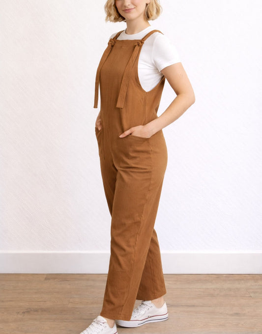 Side view of woman wearing brown Tie Detail Pocket Overall Jumpsuit against a white background.