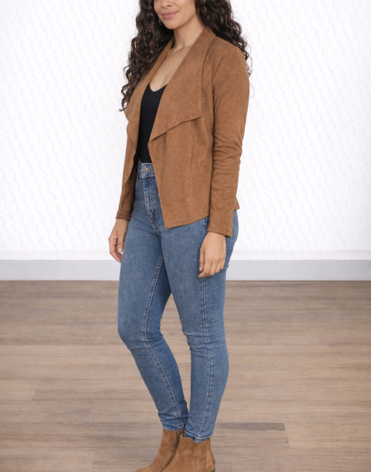 Side view of woman wearing a brown Moto Jacket, black top, and blue jeans on a white background.