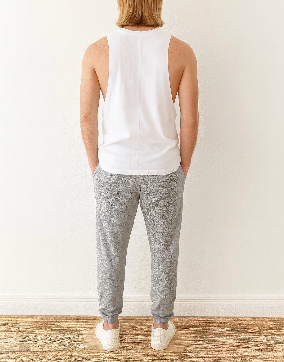 Back view of person wearing a white Workout Tank Top against a wooden wall.