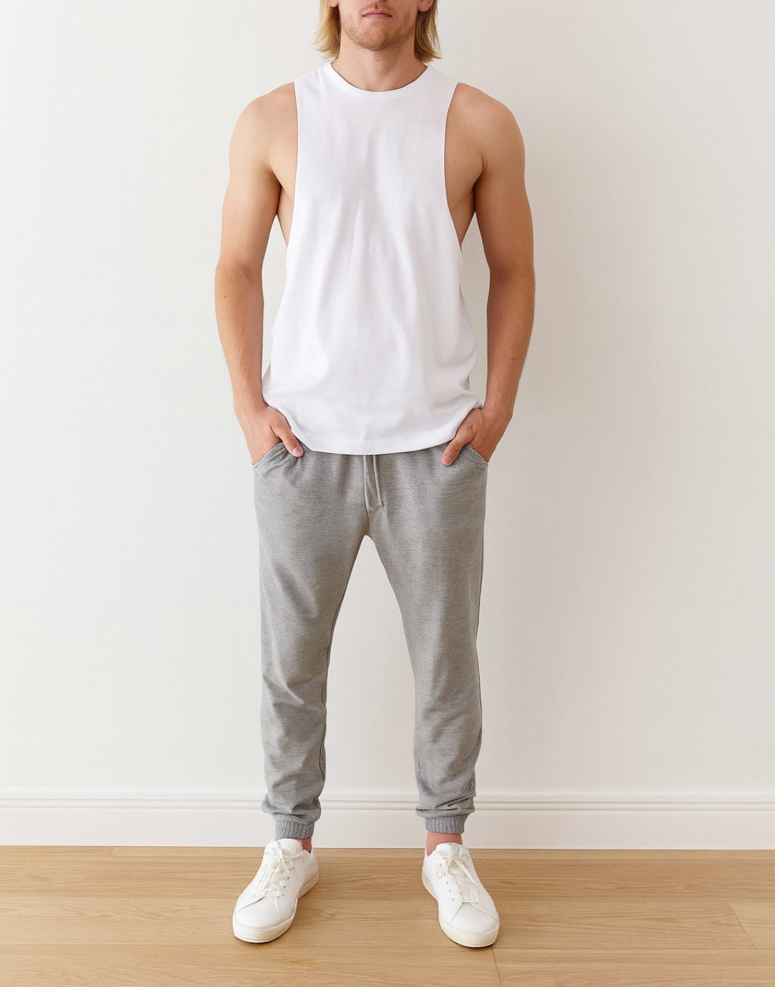 Man wearing a white Workout Tank Top against a wooden background.