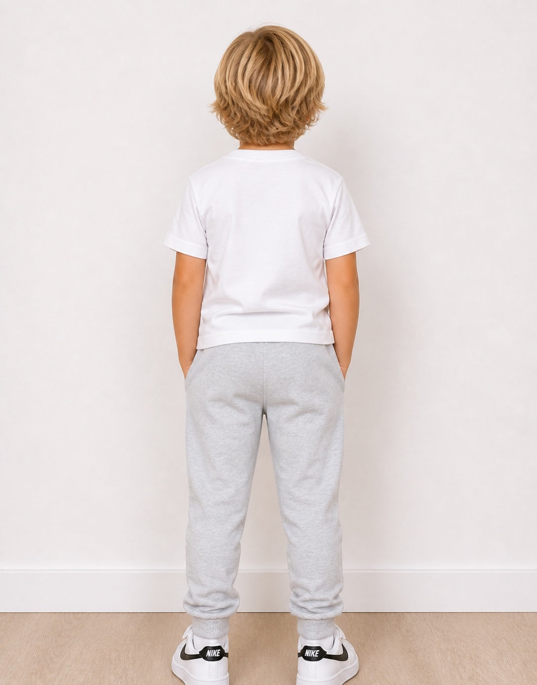 Back view of child wearing a white t-shirt and gray Jogger Pants on a plain background.