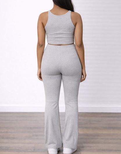 Back view of woman wearing a gray knit top and Flare Leg Knit Pants outfit with a white background.