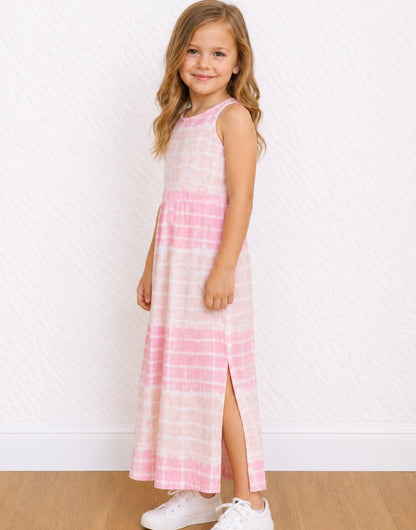 A young girl with blonde hair stands in a studio wearing a sleeveless pink and white tie-dye Maxi Tank Dress with a side slit, paired with white sneakers.