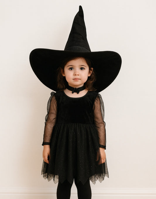 Child wearing a black witch costume with a large Witch Hat on a white background.