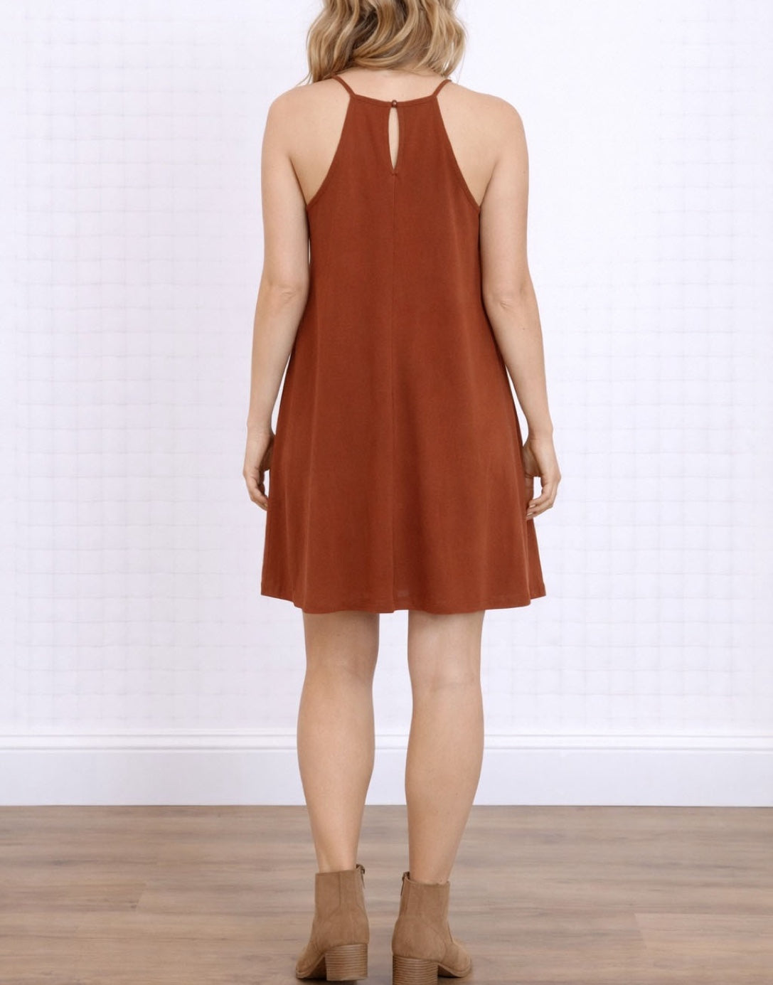 Back view of woman wearing a rust-colored Halter Cami Mini Dress against a white background. 