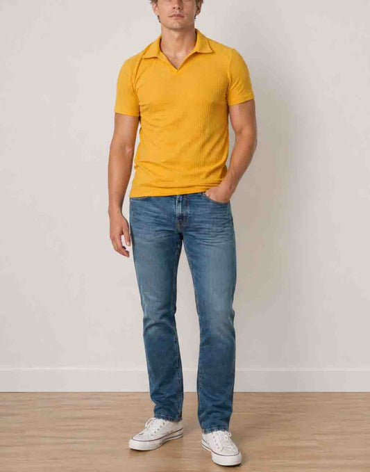 Man wearing a yellow Knit Short Sleeve Polo Shirt and blue jeans standing against a plain background