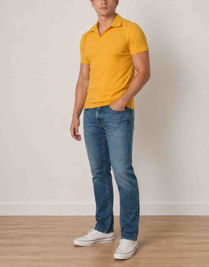 Side view of man wearing a yellow Knit Short Sleeve Polo Shirt and blue jeans standing against a plain background.