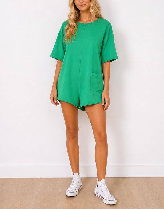 Woman wearing a green Oversized T-Shirt Romper and white sneakers on a plain background
