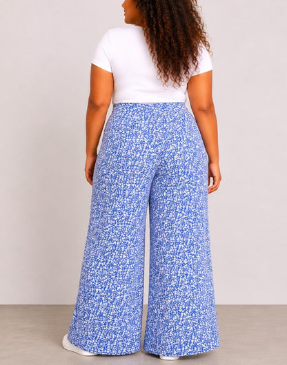 Back view of woman wearing blue floral Plus Size High Waist Wide Leg Pants and a white top against a plain background.