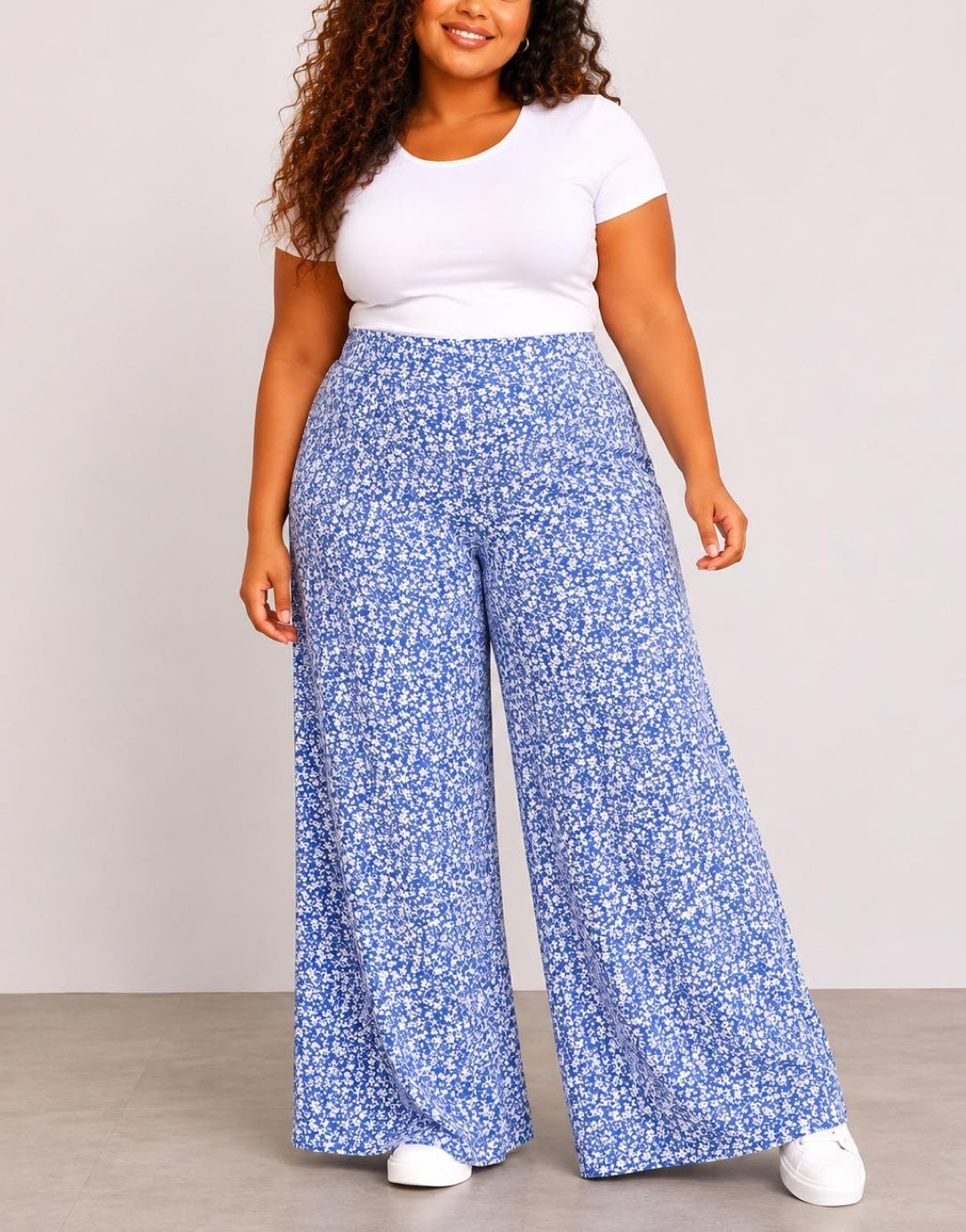 Woman wearing blue floral Plus Size High Waist Wide Leg Pants and a white top against a plain background
