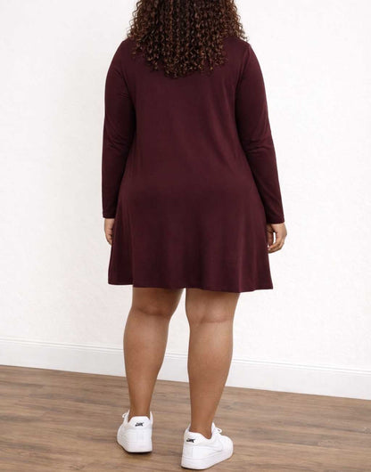 Back view of woman wearing a burgundy long-sleeve dress with white sneakers on a plain background.