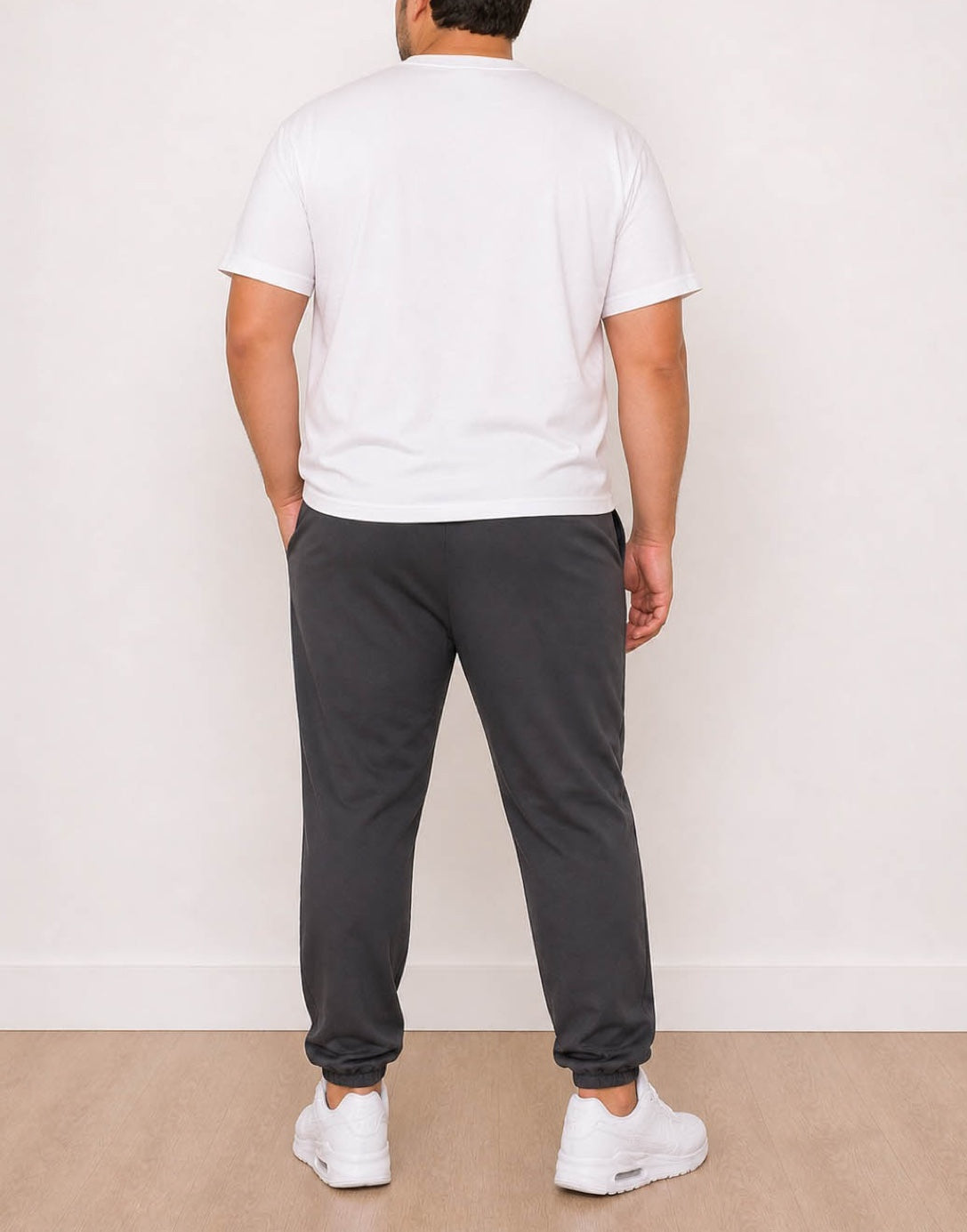 Back view of man wearing a white t-shirt and dark gray Plus Size Mens Jogger against a plain background.
