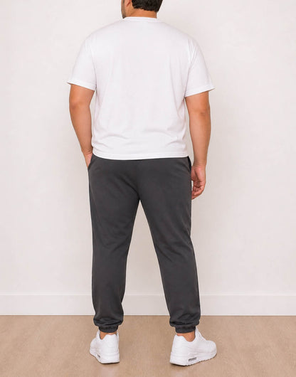 Back view of man wearing a white t-shirt and dark gray Plus Size Mens Jogger against a plain background.