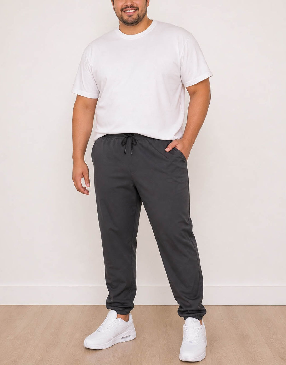 Man wearing a white t-shirt and dark gray Plus Size Mens Jogger against a plain background