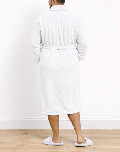 Back view of man wearing a white Plus Size Mens Shawl Collar Bathrobe and slippers on a wooden floor with a white wall background.