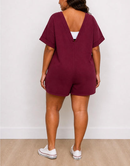 Back view of woman wearing a maroon Plus Size Oversized Tee Romper with white sneakers against a white background.