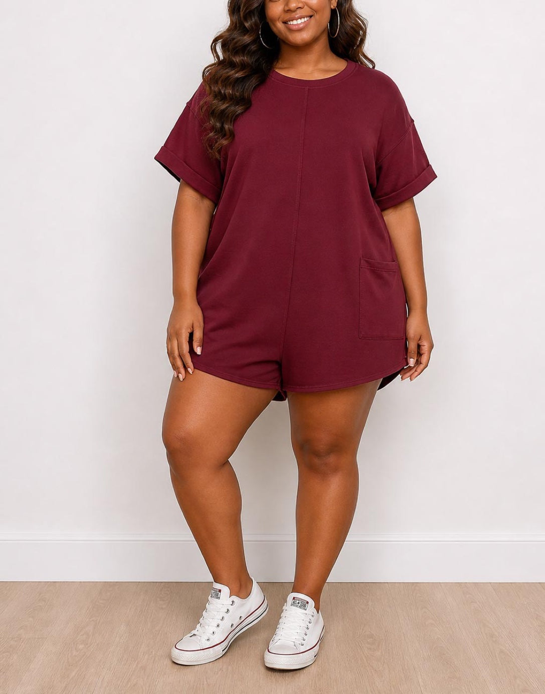 Woman wearing a maroon Plus Size Oversized Tee Romper with white sneakers against a white background