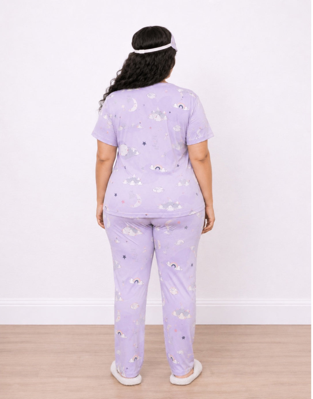 A woman viewed from the back wearing a light purple Plus Size Short-Sleeve Pajama Set with a small cloud print, standing against a plain white wall on a light wood floor.