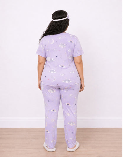 A woman viewed from the back wearing a light purple Plus Size Short-Sleeve Pajama Set with a small cloud print, standing against a plain white wall on a light wood floor.