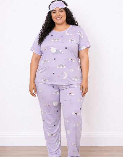 A woman modeling a light purple Plus Size Pajama Set with a matching sleep mask. The pajamas feature a whimsical print of clouds, stars, and rainbows.