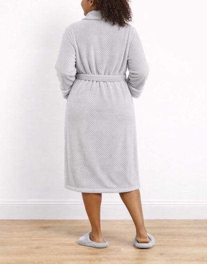 Back view of woman wearing a gray Plus Size Shawl Collar Bathrobe and slippers on a wooden floor with a white wall background.