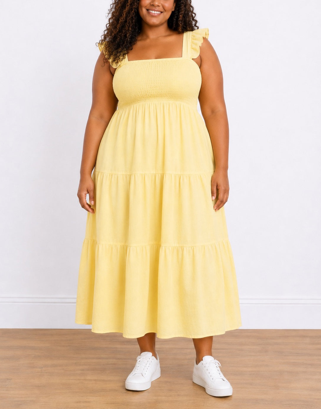 Woman wearing a yellow Plus Size Shirred Maxi Dress with white sneakers on a wooden floor.