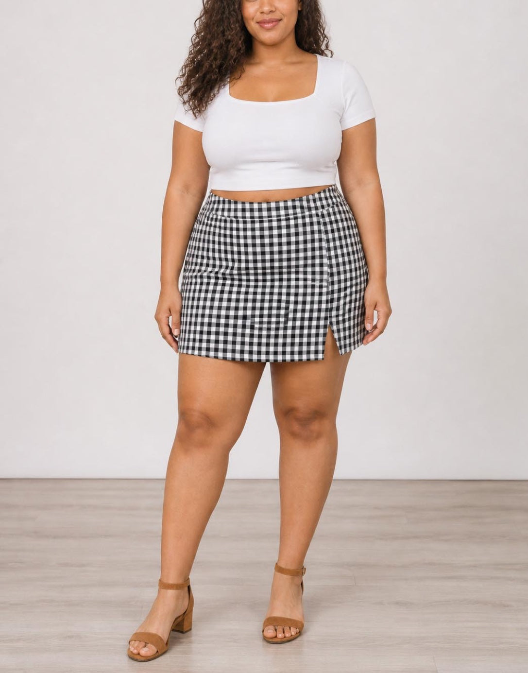 Woman wearing black and white gingham Plus Size Split Hem Skort with white top.