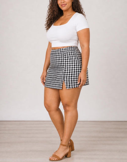 Side view of woman wearing black and white gingham Plus Size Split Hem Skort with white top.